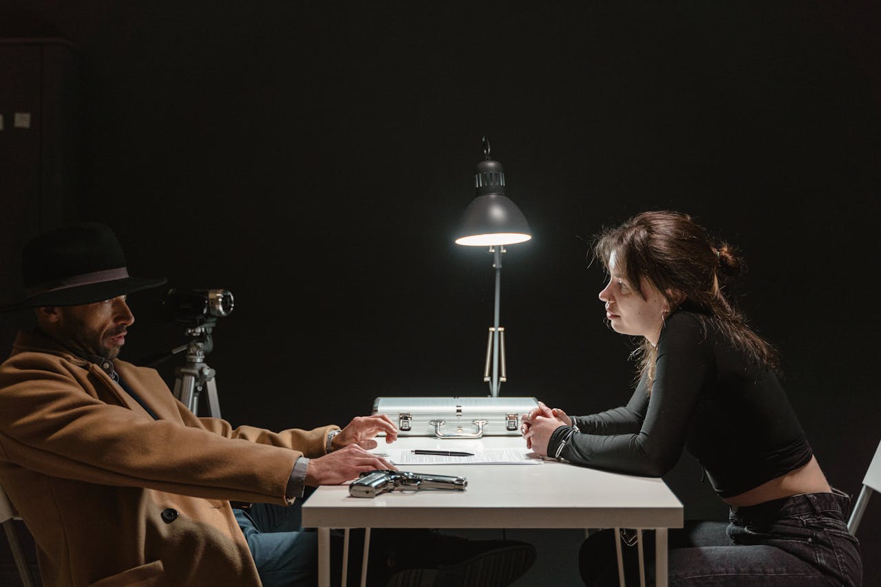 digital Tense interrogation scene with a man and woman in a dark room under harsh lighting.